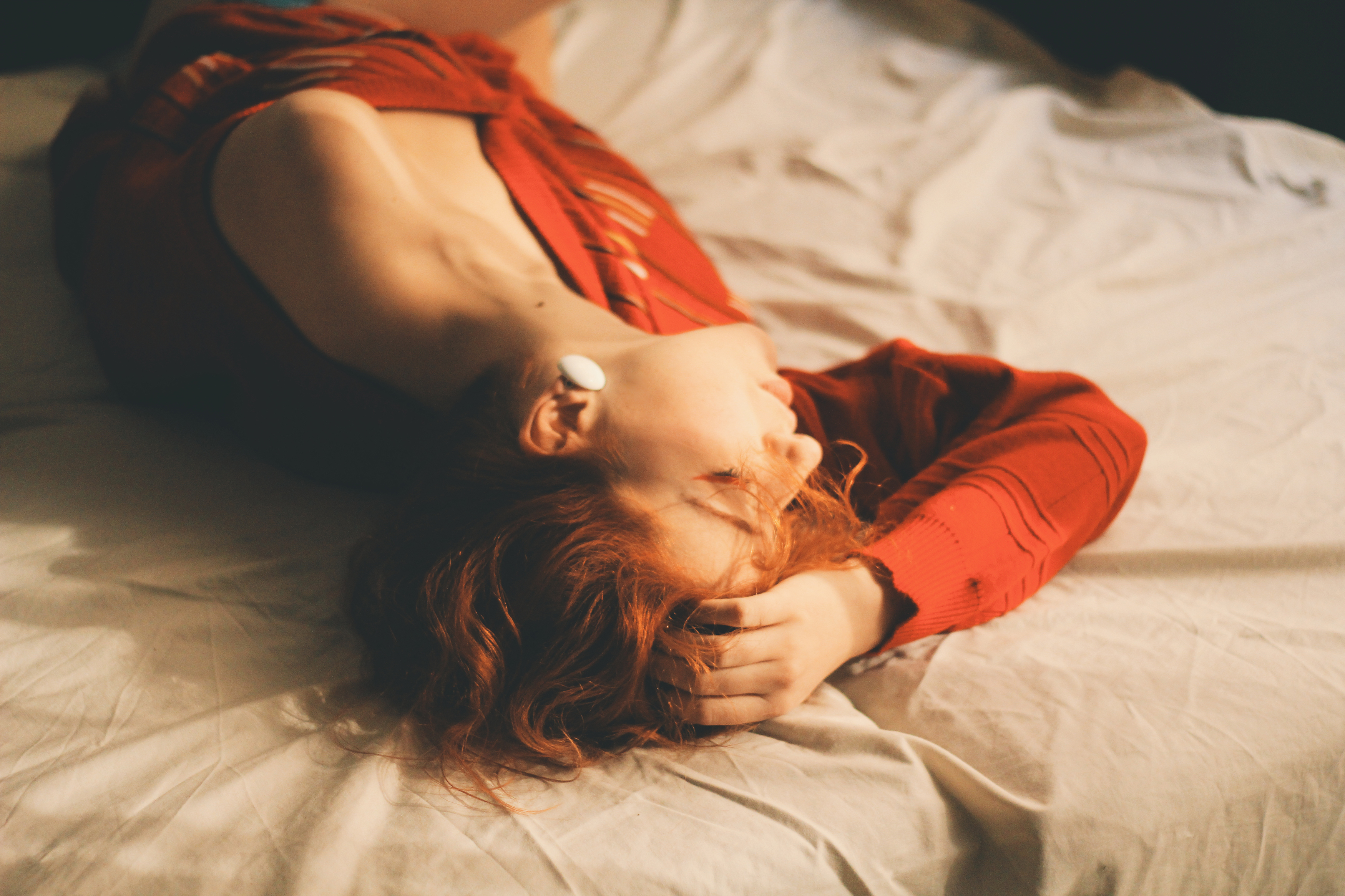 Полная дама с рыжими волосами ласкает себя пальцами на кровати